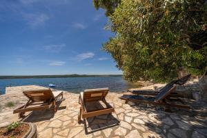 a group of chairs sitting on a beach next to the water at Holiday Home Baricevic in Posedarje