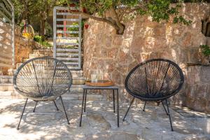two chairs and a table in front of a stone wall at Holiday Home Baricevic in Posedarje