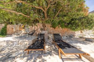 two chairs and a table under a tree at Holiday Home Baricevic in Posedarje