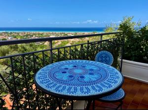 a blue table and chairs on a balcony with the ocean at B&B Il Tramonto in Capo dʼOrlando