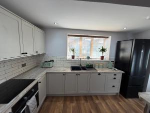 a kitchen with white cabinets and a black refrigerator at 3 bed detatched cottage with onsite parking in Rotherham