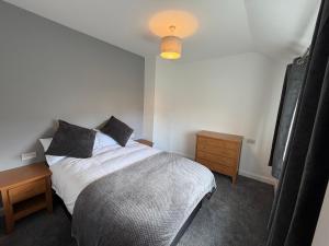 a bedroom with a bed with black pillows and a lamp at 3 bed detatched cottage with onsite parking in Rotherham