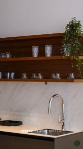a kitchen counter with a sink and glasses on shelves at K1959 Studio Suites in Peje