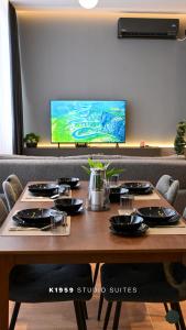 a table with chairs and a television in a room at K1959 Studio Suites in Peje