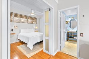 a white bedroom with a bed and a mirror at Kona Mansions#208 in Kailua-Kona