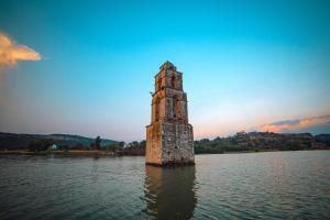a stone tower in the middle of a body of water at Hotel El Aguila, Villa del Carbón in Villa del Carbón