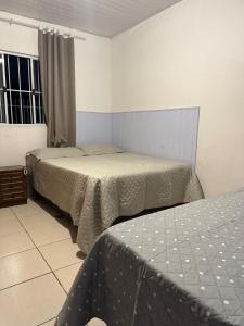 a bedroom with two beds and a window at Casa Completa in Curitiba