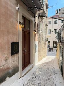 an alley with a brown door on a building at The Elysium Rooms in Makarska