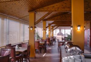 a restaurant with wooden ceilings and tables and chairs at Mariam Hotel in Madaba