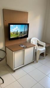 a living room with a tv and a white chair at Boulevard Park in Caldas Novas