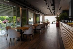 a restaurant with wooden tables and chairs and windows at Vila Inheritor in Shëngjin
