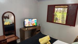 a room with a tv and a mirror and a bed at Haras Cristal Experience in Gama