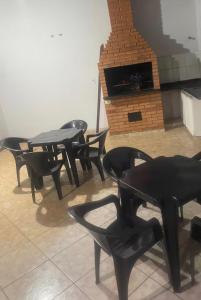 four black tables and chairs in a room with a fireplace at Sua casa longe de casa in Anápolis
