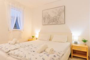 a white bedroom with a bed and a window at Lumbarda Resort Apartments in Lumbarda