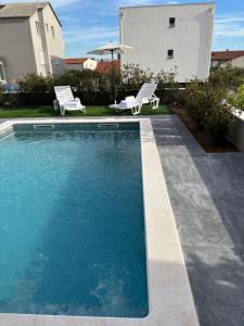 a swimming pool with two chairs and an umbrella at Albatros in Kastel Sucurac