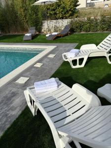 two white lounge chairs next to a swimming pool at Albatros in Kastel Sucurac