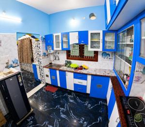 a kitchen with blue cabinets and a black and white floor at Eden Villa in Virāmpattinam
