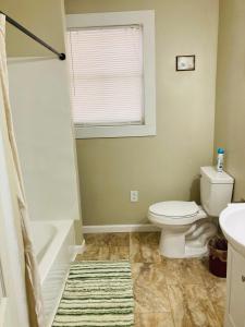 a bathroom with a toilet and a tub and a sink at The Humble House in Martinsville