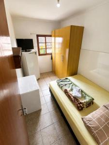 a small bedroom with a bed and a refrigerator at Pensão Meg in São José