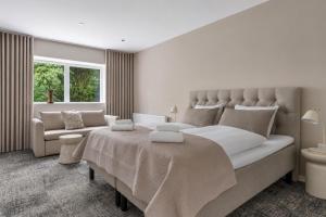 ein weißes Schlafzimmer mit einem großen Bett und einer Couch in der Unterkunft Hotel Kongens Ege in Randers