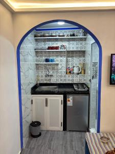 a kitchen with an archway with a counter and a refrigerator at Casa Inass blue in Chefchaouen