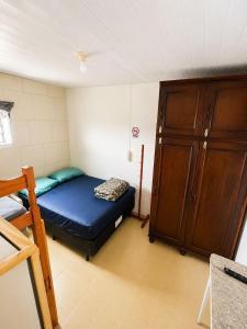 a small room with a bed and a wooden cabinet at Pensão Meg in São José