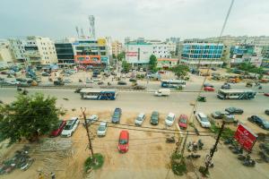 a parking lot with cars and buses in a city at Ravila Grand Hotel in Lingampalli