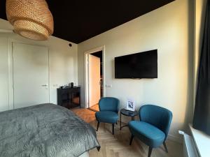 a bedroom with a bed and two blue chairs at Logement Langestreek in Lemmer