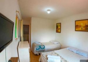 a room with two beds and a flat screen tv at Suites Mar a Vista in Porto De Galinhas