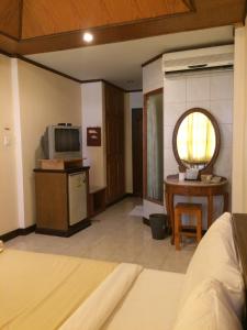 a room with a bed and a television and a table at Kraisaeng Place in Phitsanulok