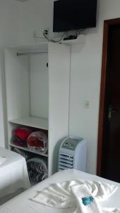 a bedroom with a bed and a tv on a wall at Hotel Maciel in Ponta Grossa