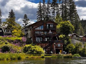 a wooden house with a balcony on the river at THE INN Bigfork Bay in Bigfork