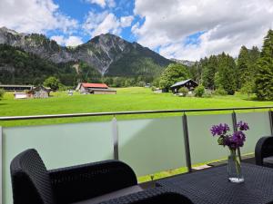 a table with flowers on a balcony with mountains at Ferienwohnung Stelzis in Wald am Arlberg
