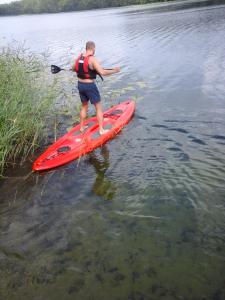a man standing on a red kayak in the water at Pas Kaziuką namukas in Palūšė
