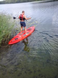 a man standing on a red kayak in the water at Pas Kaziuką namukas in Palūšė