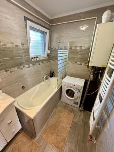 a bathroom with a tub and a washing machine at Ditta Home in Nyíregyháza +7 photos
