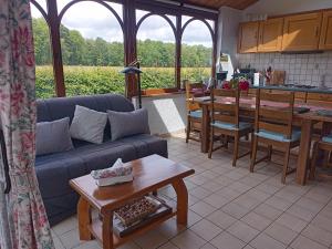 a living room with a couch and a table and a kitchen at Le Clos Fleuri in Sautin