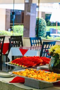 a table with trays of food on top at Safira Praia Hotel in Porto Seguro