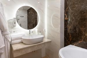 a white bathroom with a sink and a mirror at Leomare in Odesa