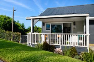 a small house with a white railing and a porch at Die Fijnbos in Glentana +16 photos