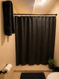 a bathroom with a black shower curtain and a toilet at Casa Di Manuelito in Monterrey