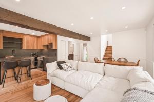 a living room with a white couch and a kitchen at 206 Val-des-Neiges - MSA LUX in Beaupré