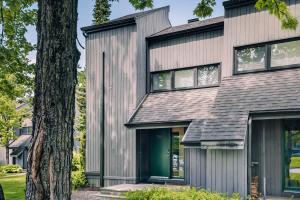 a house with a green door and a tree at 206 Val-des-Neiges - MSA LUX in Beaupré
