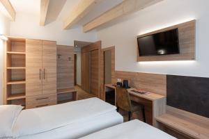 a bedroom with a desk and a tv on the wall at Hotel Alpen in Andalo