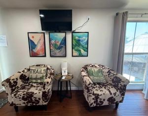 a living room with two chairs and a tv at HT Innhabit rooftop view suite in Medicine Park