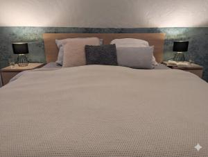 a large white bed with pillows and two lamps at Ferienwohnung Rheinwald in Hartheim