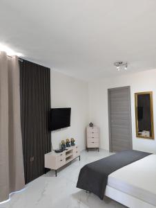 a white bedroom with a bed and a television at Shamrock Flats in Mellieħa