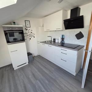 a small kitchen with white cabinets and a sink at Im Buchenweg in Großheubach +8 photos