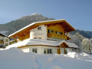 a snow covered building in front of a mountain at Haus Muntschnei in Sankt Gallenkirch