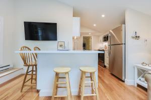 a kitchen with a bar with stools and a refrigerator at Granite Cottage in Rockport